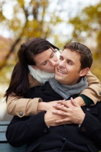 Woman giving man sitting on bench a kiss