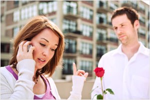 Woman on cell phone ignoring man with rose