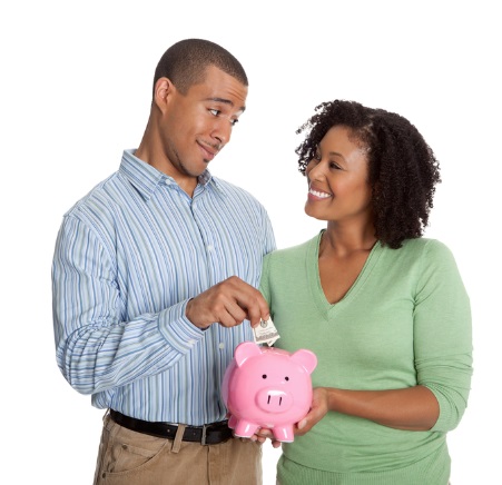 Happy couple feeding a piggy bank