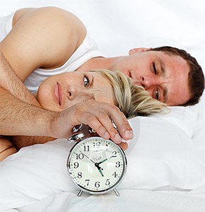 Couple in bed with clock.