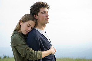 Women hugging man from behind while he looks into the distance.