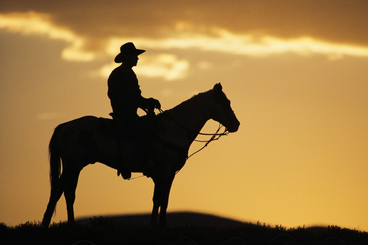 cowboy riding into sunset