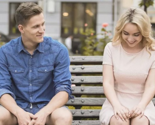 man and woman flirting on bench