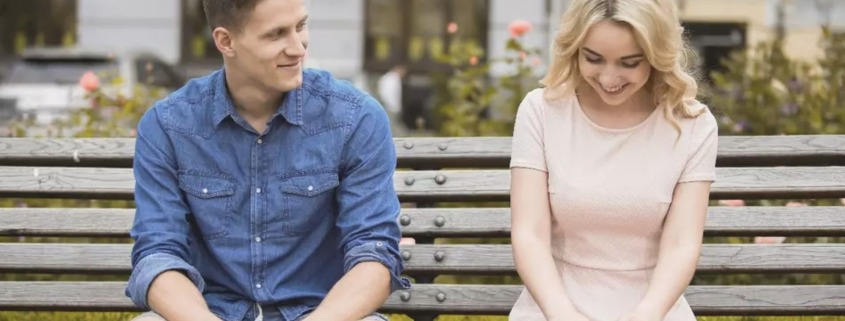man and woman flirting on bench